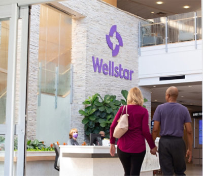 两个人走在 Wellstar 接待处前。