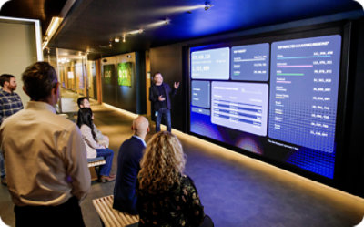 Professionals in modern conference space at Microsoft Digital Crimes Center, viewing cybersecurity presentation display