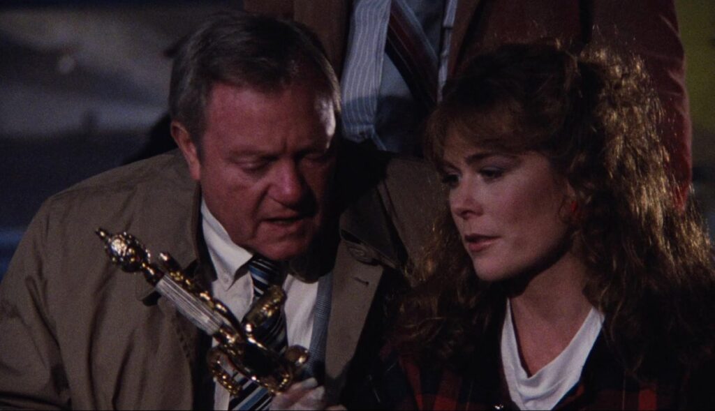 police detective and pretty red haired woman checking out a sword in a parking garage