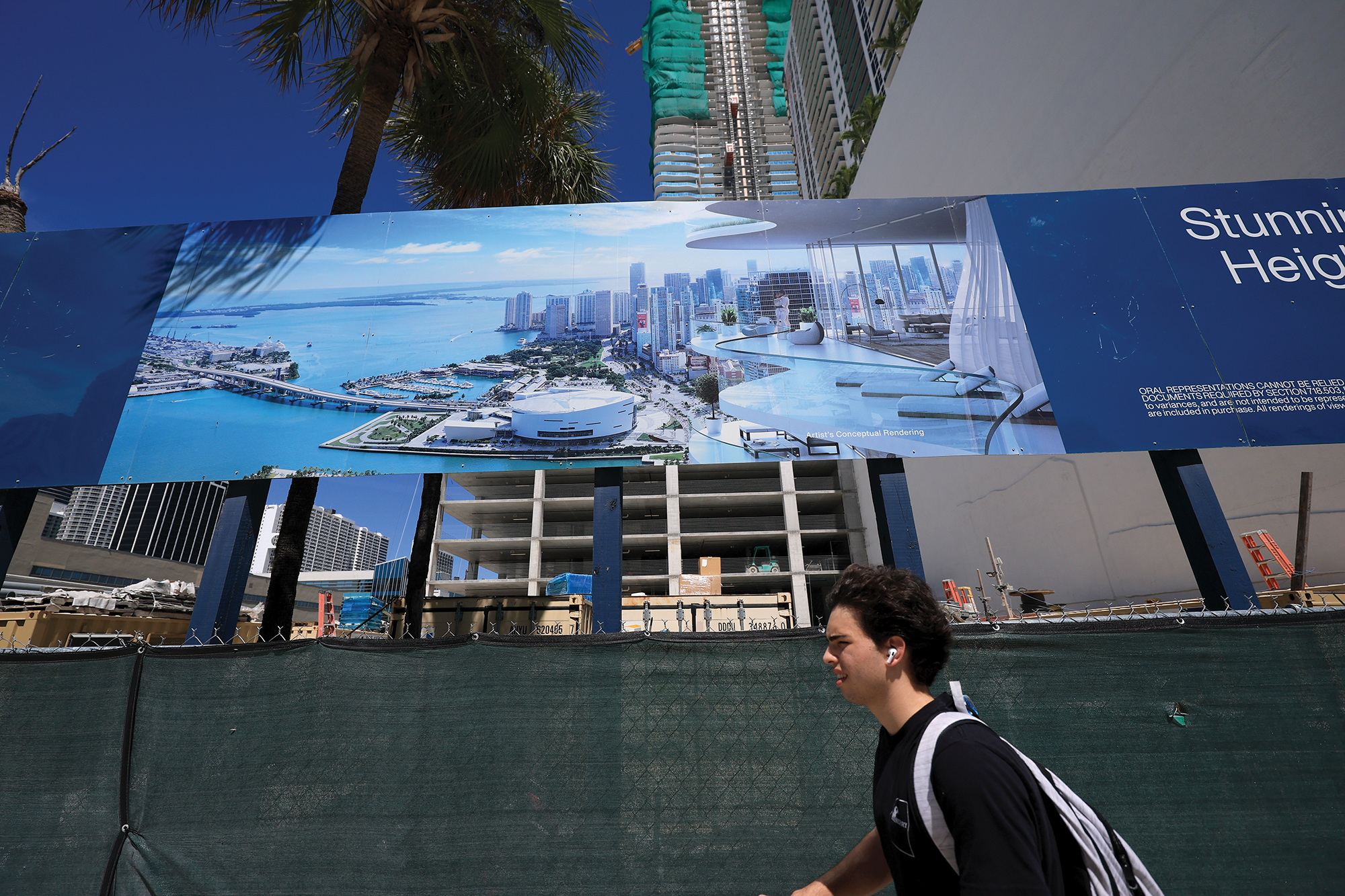 Pedestrians pass by a billboard featuring a condo building being built in downtown in Miami in August 2025.