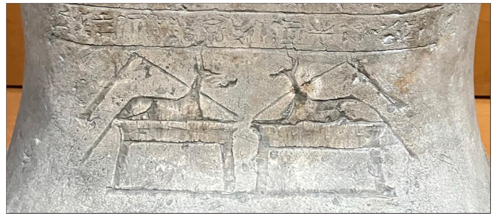 Fig. 7: The recumbent jackals on the ankles of the sarcophagus lid. (Photograph by Melinda Hartwig)  At the ankles are two jackals on low rectangular shrines, oriented to be seen by the viewer. Each has a flail diagonally over its back, with the bottom of the handles attached to the fronts of the shrines. This unusual detail can also be seen on the sarcophagus of Padihornedjitef (Cairo TR 15.1.21.6), where the jackals are also oriented to be seen by the viewer. The jackals are not labelled here; in other examples they can be identified as either Anubis (Imiut and Khenty-sah- netjer) or Wepwawet. In either case, they likely represent addition protection for the deceased, as well as the psychopomps who will usher Isetirdiset into her life after death.“  