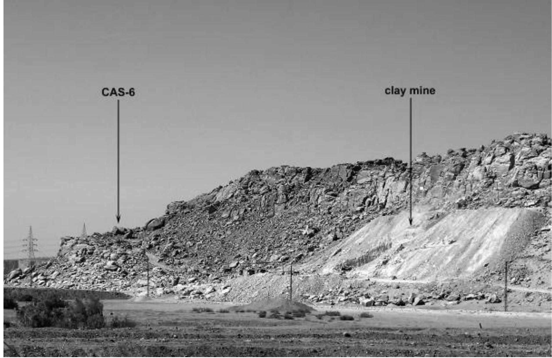 Figure 4: A view of Wadi Abu Subeira with localisation of the Late Palaeolithic rock art site CAS-6 and a modern clay mine in operation (photograph: P. Storemyr).  There are several others threats to Egyptian rock art. Because of newly constructed roads, both along the Nile Valley and traversing the Eastern Desert, and the intensification of four-wheel-drive off-road traffic, human presence at the rock art locations has substantially increased during the past few years. Several cases of deliberate destruction and vandalism have been witnessed (Fig. 7.5) (see, e.g., Bahn 2010: 178- 179). While some examples of theft are known, this seems to be a relatively minor issue when compared to other parts of North Africa, such as Morocco (Salih 2007). Large-scale fertilising projects and the implantation of a huge industrial infrastructure, notably for the production of phosphates, are rapidly transforming the lower desert areas along the Nile Valley into featureless plains and pockmarked wasteland. At Elkab in Upper Egypt, for instance, an ever-expanding phosphate plant is now threatening several important rock art sites, including the famous Borg el-Hamam with dozens of Predynastic drawings and hieroglyphic rock inscriptions (Huyge 1984; Hendrickx & Huyge 1989: No. 77). Unless local antiquities authorities take immediate, urgent action, these sites are doomed to disappear in the short- term. 
