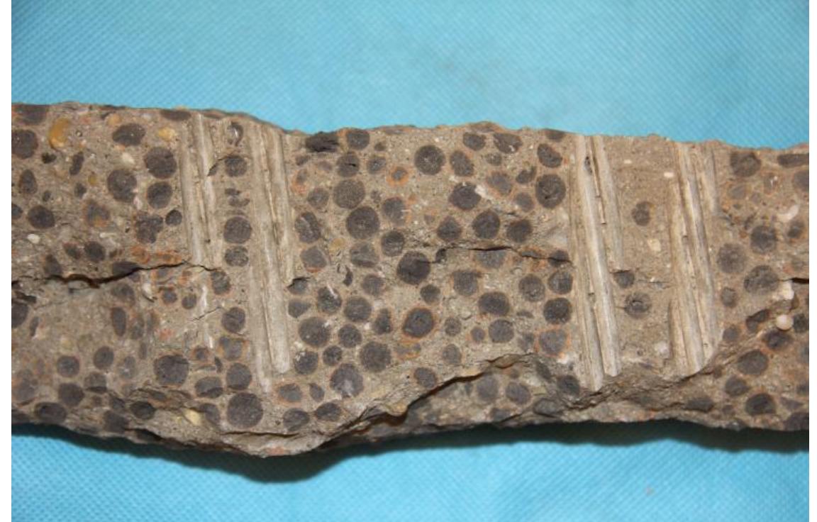 Figure 8. Bond of 7 wire strands in the precast LWAC girder (photo was taken after failure)  The concrete was cast according to the specified mix, but with wet LWA (water content 9.3 percent by mass). The required amount of concrete could be mixed in two batches and compacted by concrete formwork vibrators. It was demoulded after one day. The beam behaved in the test in accordance with the calculations. Figure 8 gives an indication of bond of 7 wire strands in the LWAC girder as well as the distribution of lightweight aggregates around the prestressing wires. 