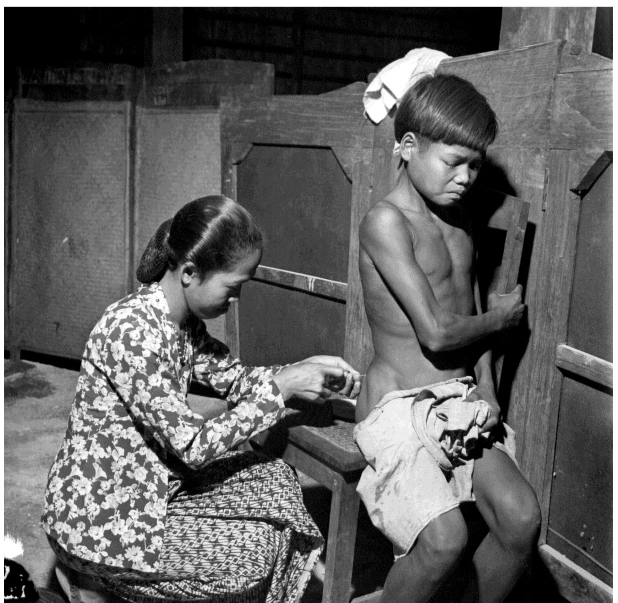 A Javanese nurse (left) treats a young boy with penicillin in the regency of Karangsem, Bali.