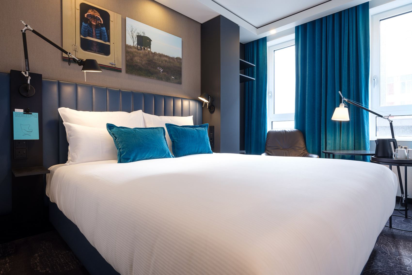 designhotel Glasgow Motel One bright room with a large double bed and an armchair with a side table