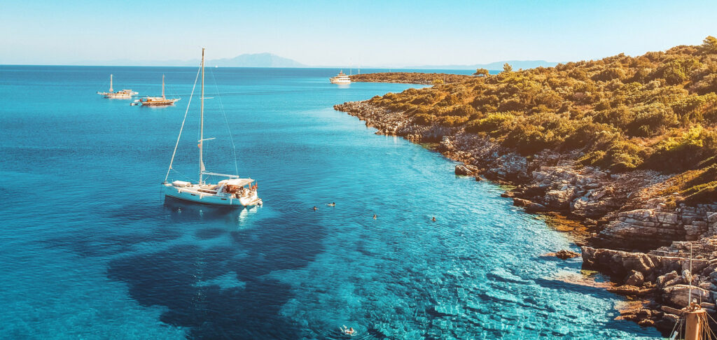 Swimmers from a sailboat relax in the blue water off Orak Island.