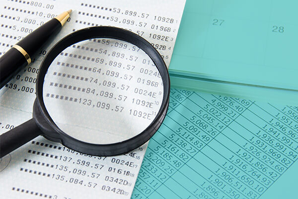 Magnifying glass laying over expense paperwork