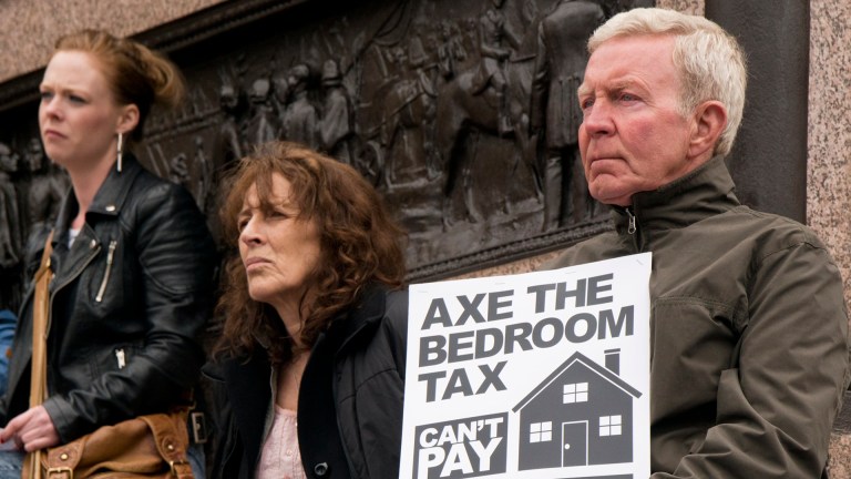 protesters hold up a placard calling for leaders to axe the bedroom tax