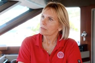 Captain Sandy on her boat wearing a red shirt looking upset.