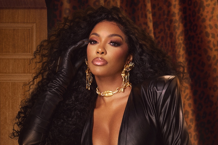 Porsha Williams standing in an ornate room with brown decor.