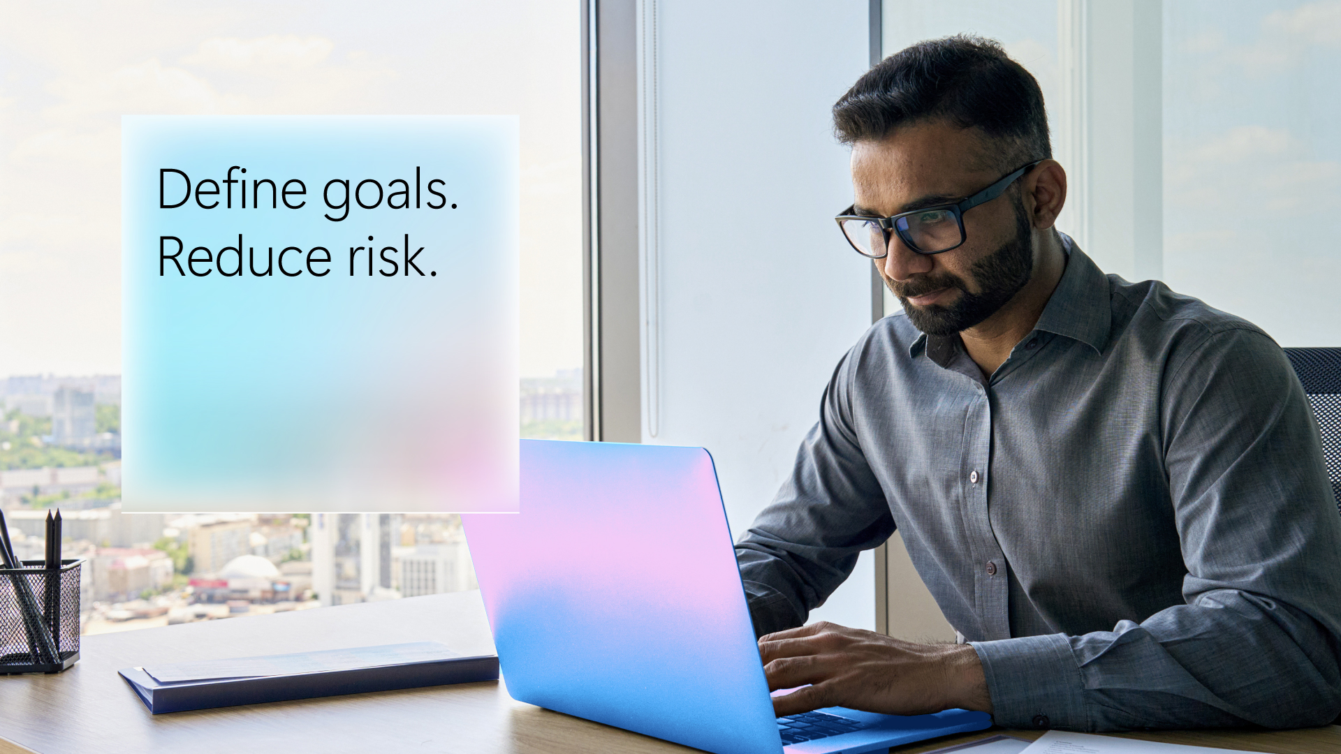 A man looks at a laptop screen. The words "define goals, reduce risk" are in the corner.