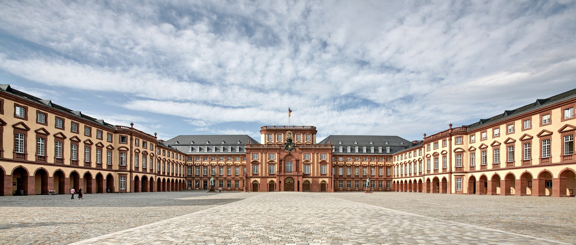Universität Mannhei mit Ehrenhof an einem sonnigen und bewölkten Tag.